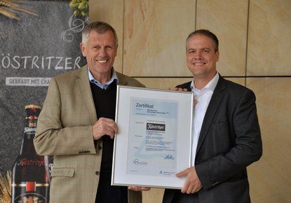 Geschäftsführer Albrecht Pitschel nimmt das Zertifikat Nachhaltiger WirtschaftenFood von Dr. Axel Kölle, Leiter des ZNU, entgegen.