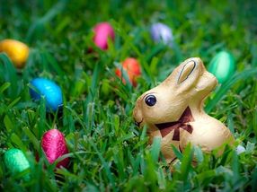 Conejo de Pascua de chocolate en papel de aluminio sentado en la hierba