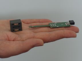 El imán permanente a la izquierda y la placa de circuito verde junto a él, que lleva un diminuto sensor cuántico integrado en un chip a la izquierda.